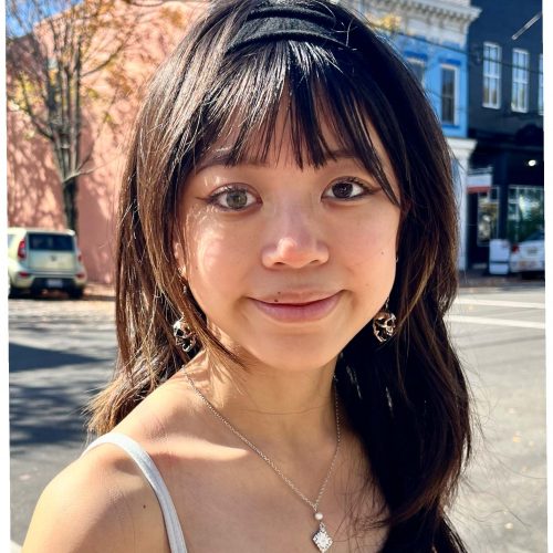 Front profile of Ayla Bramblett with long dark hair and eyes posing on a street.