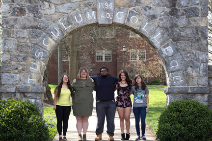 five students standing under stone arch