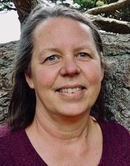 Front profile of Karen Fisher with shoulder length brown hair wearing a maroon shirt.