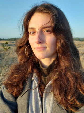 Mirela Music headshot young woman with long hair against blue sky