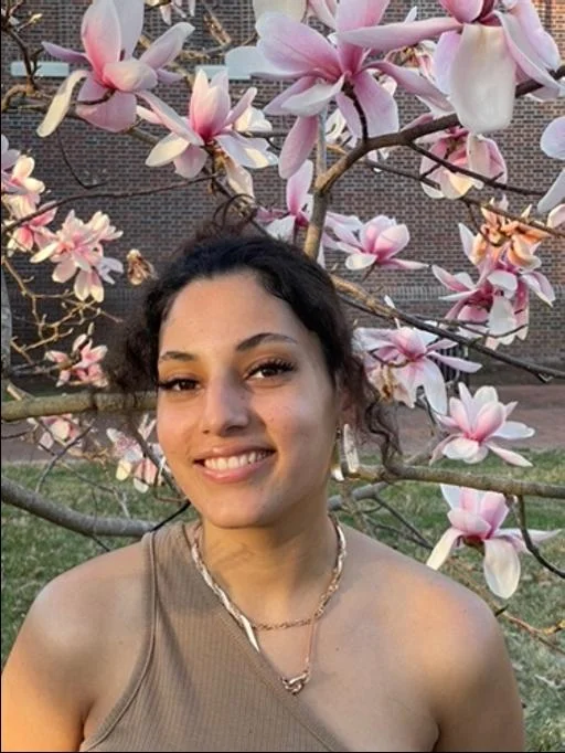 Front profile of Siobhan Jean-Charles with dark brown hair pulled up and a flowering tree in the background.